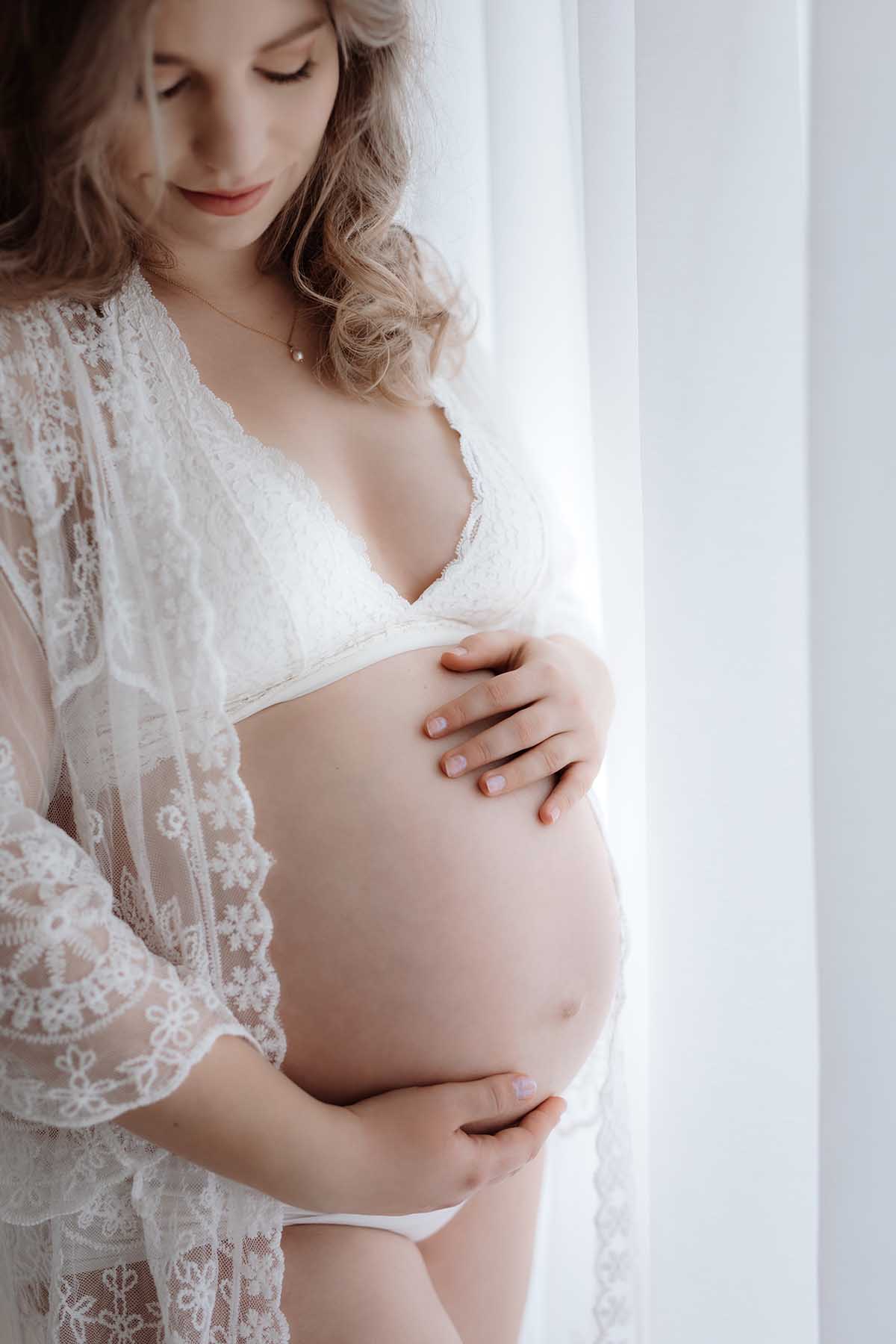 eine schwangere in einem Fotostudio mit einem Spitzenkimono 