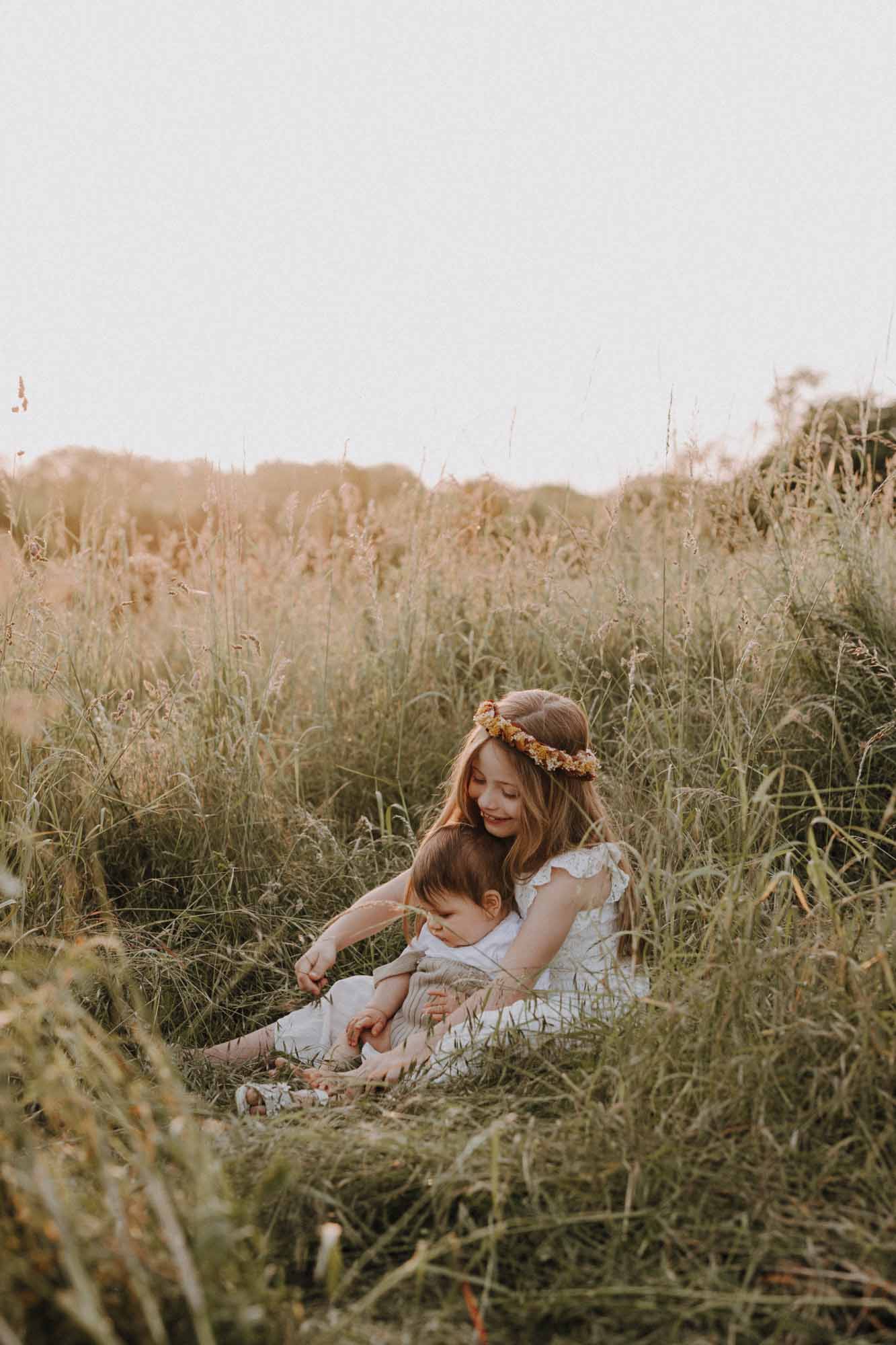 ein Mädchen sitzt mit ihrem kleinen Bruder im gras